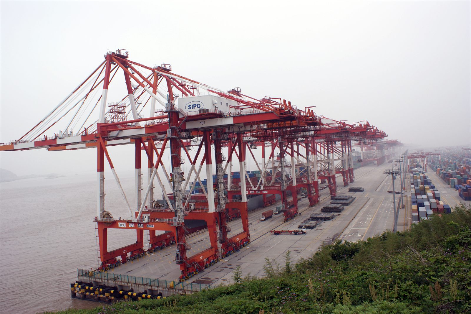 Stacked shipping containers and gantry cranes at the Yangshan deep-water container port near Shanghai, China