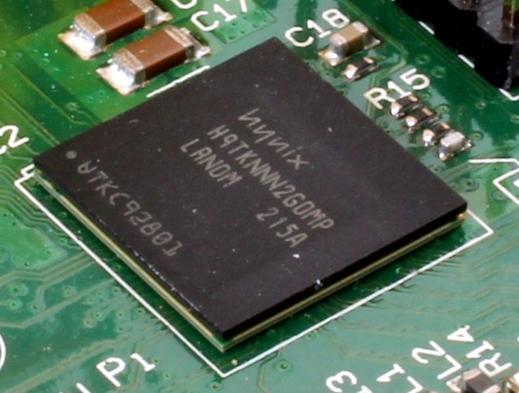 A close-up of a small black system-on-chip package soldered to a green circuit board.