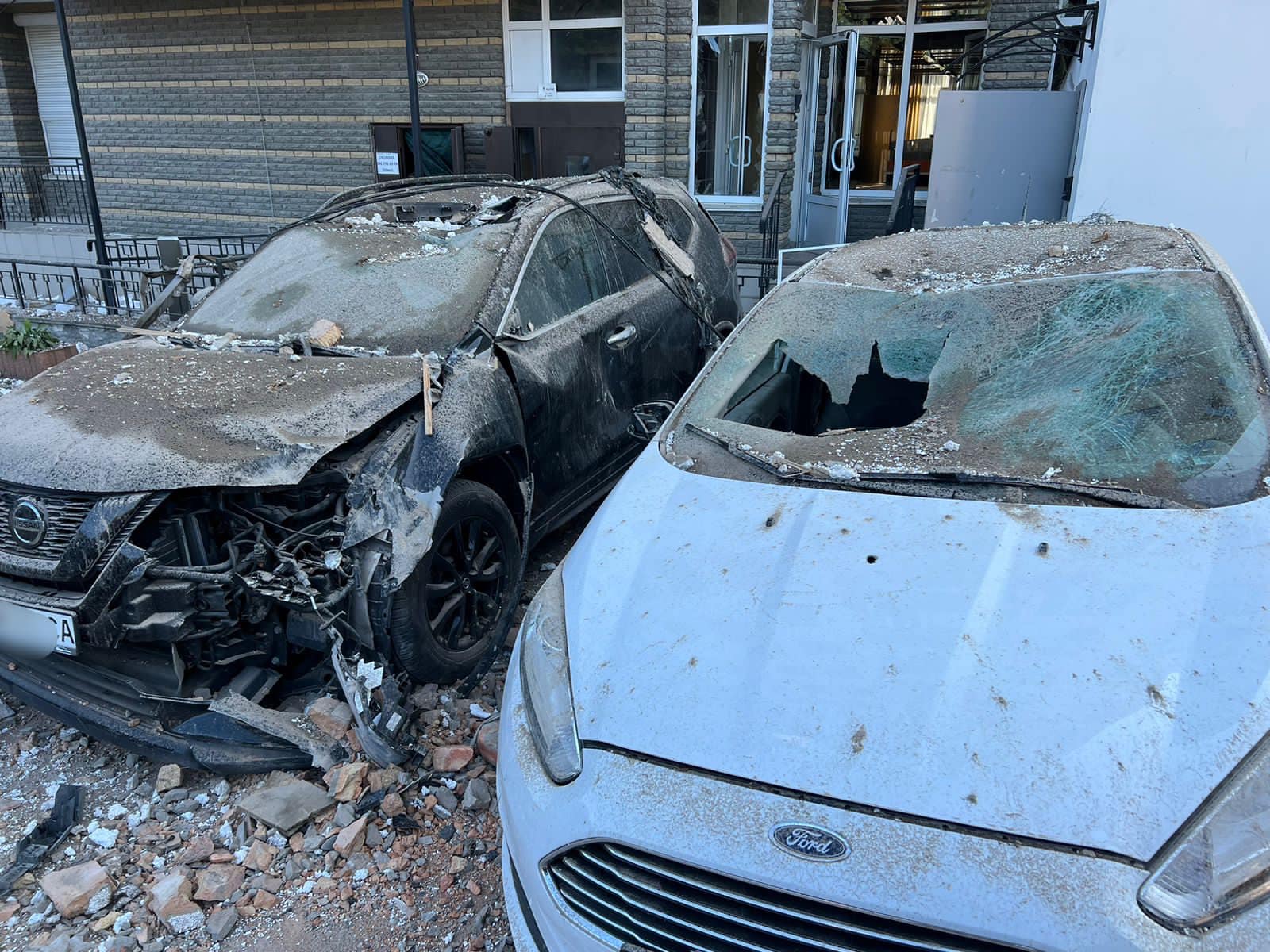 National Police of Ukraine / Wikimedia Commons · CC BY 4.0 Burnt-out cars in front of a Kyiv apartment block, its lower storeys blackened by fire after a night-time drone attack